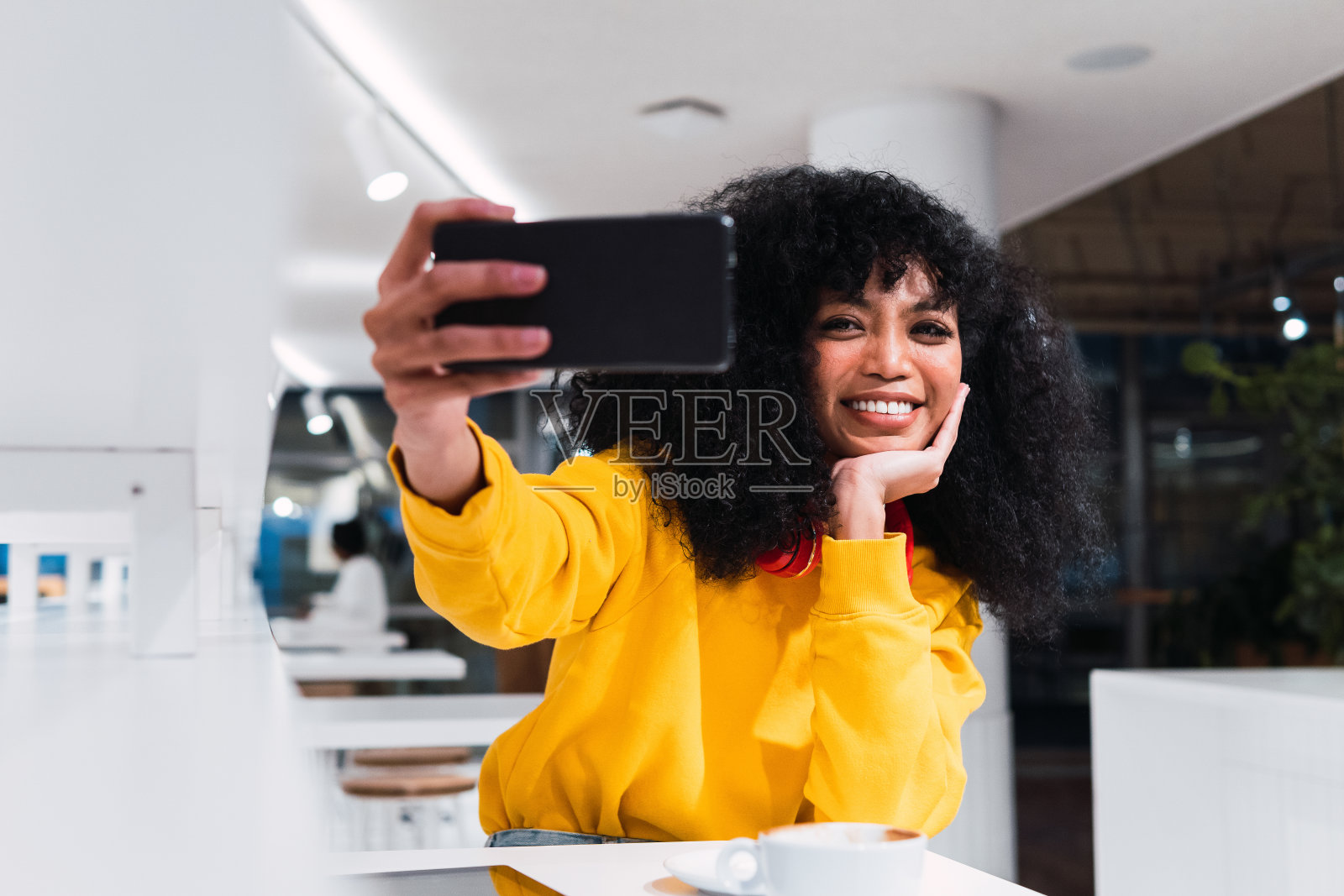 兴奋的年轻少数民族妇女微笑着在咖啡馆自拍照片摄影图片