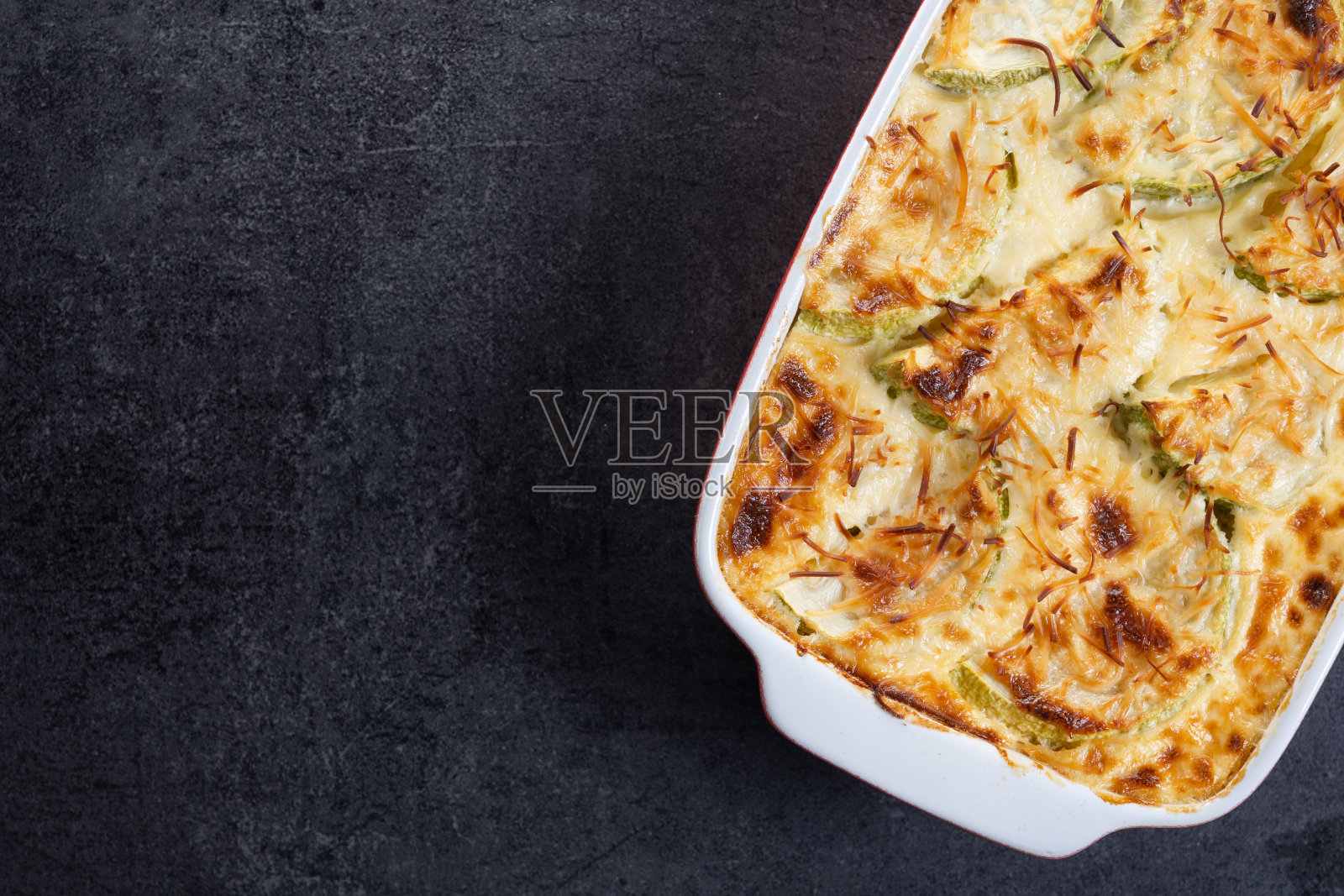 在黑色石板背景上，用奶油和奶酪烤土豆照片摄影图片