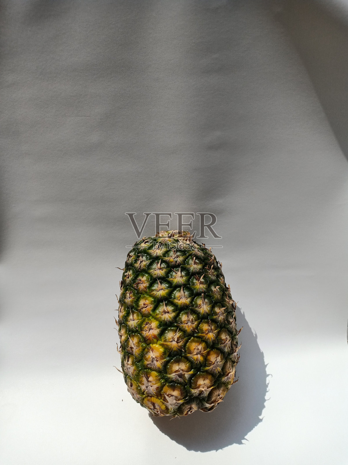 特写的新鲜菠萝水果与绿色的皮肤在一个白色的背景照片摄影图片