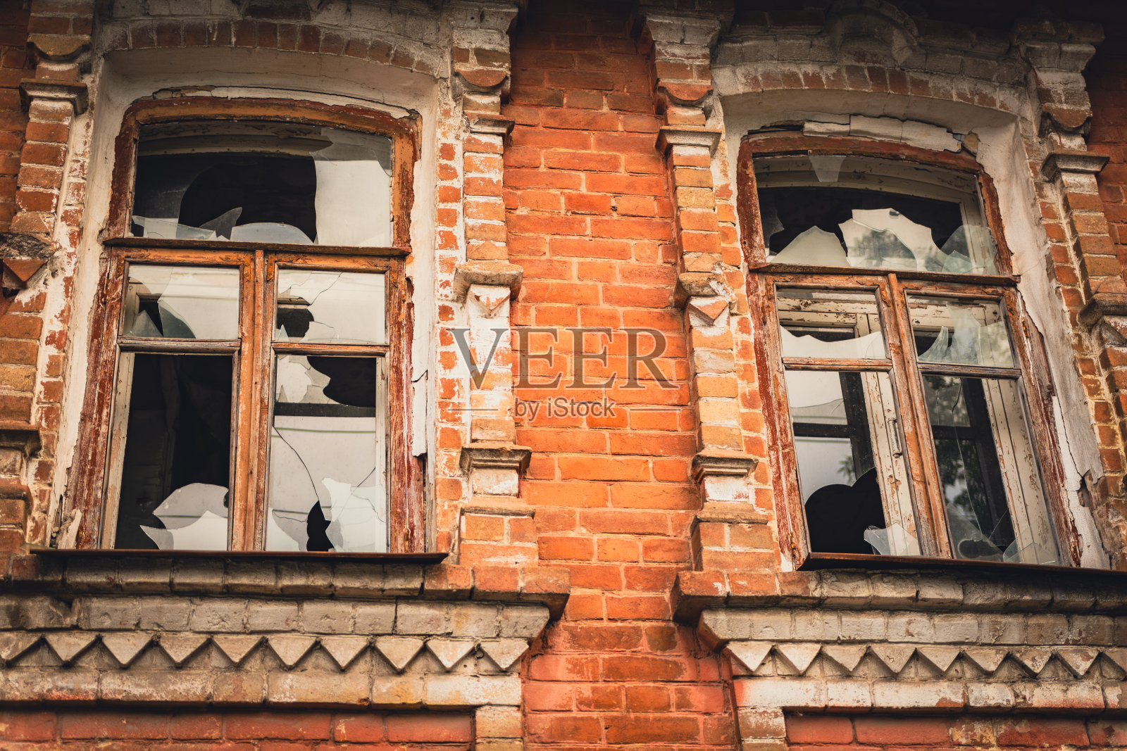 废弃的老式建筑，白天有风化的窗户和破碎的砖立面照片摄影图片