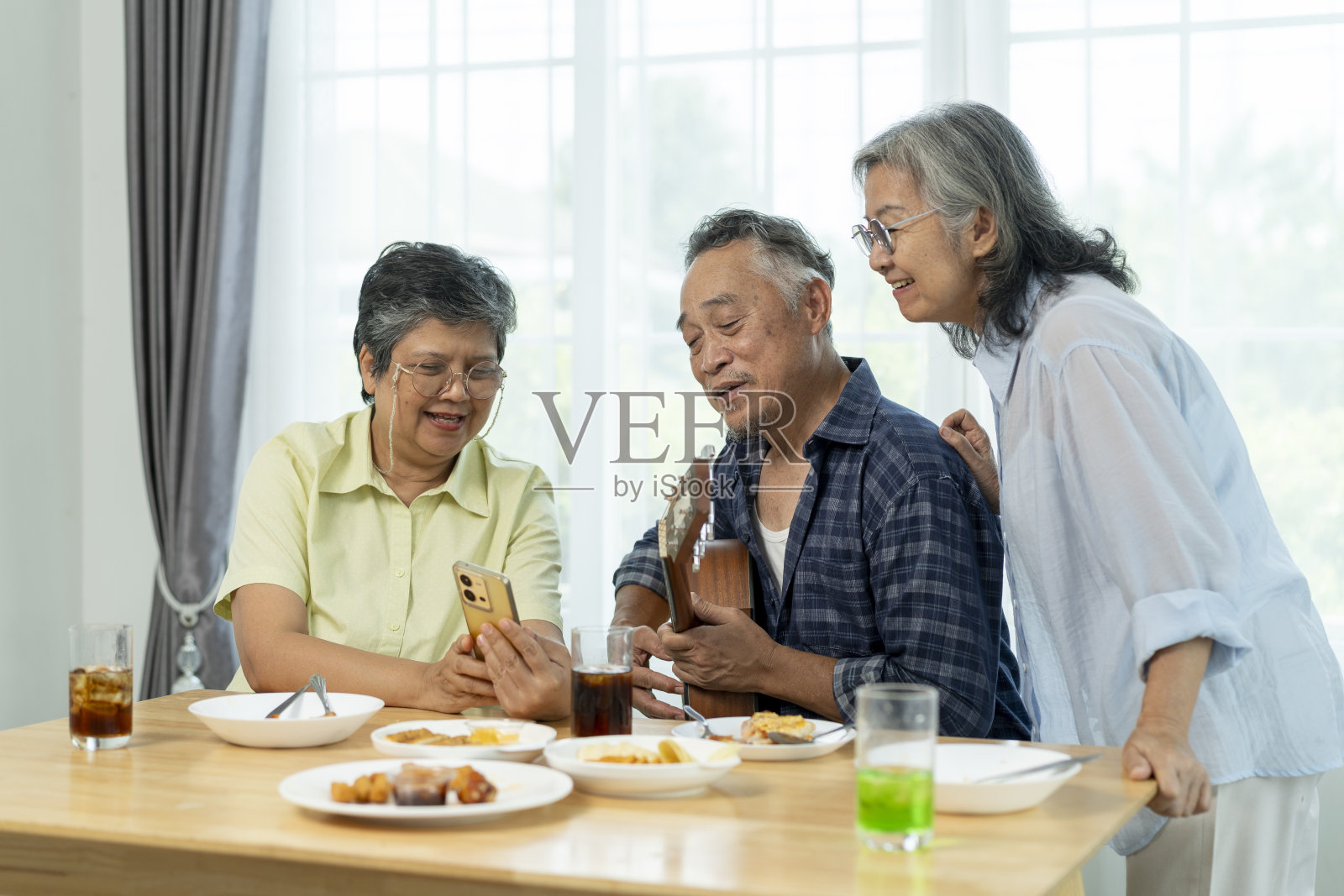三个高年级的朋友在聚会上通过音乐、唱歌和笑声联系在一起照片摄影图片