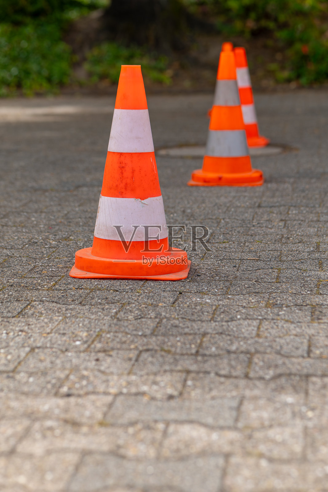 橙色和白色的交通锥排列在一条砖路上照片摄影图片