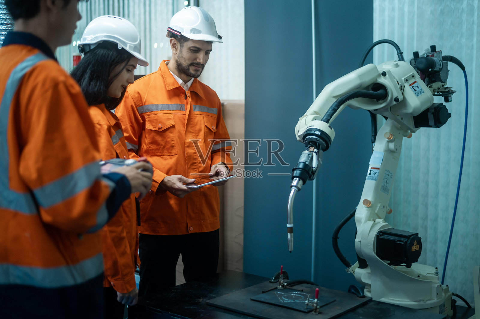 一群机器人工程师从事编程和操纵机械手，工业机器人设计，高科技设施，现代机器学习。大规模生产自动化。照片摄影图片