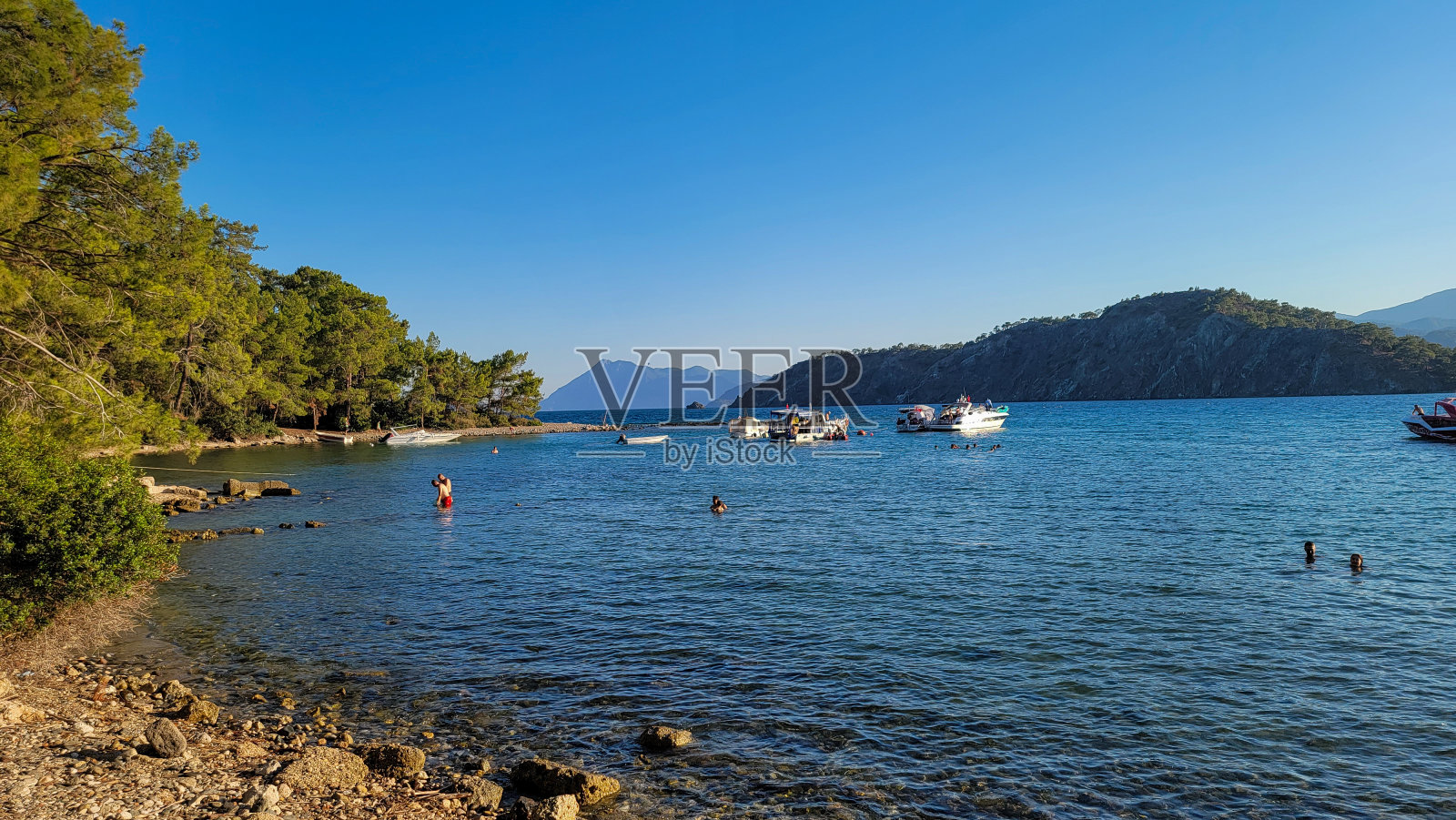 可以看到山、海、船和人们在洗澡照片摄影图片