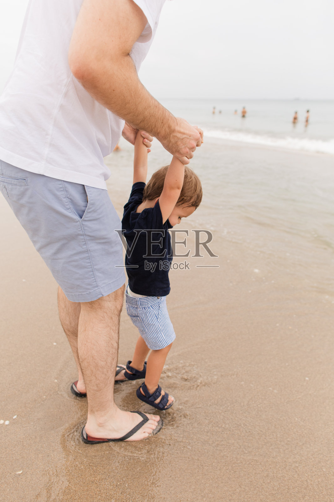 佛罗里达州棕榈滩，一个阴天的夏日午后，一位33岁的父亲和他两岁的儿子在海滩上玩耍照片摄影图片