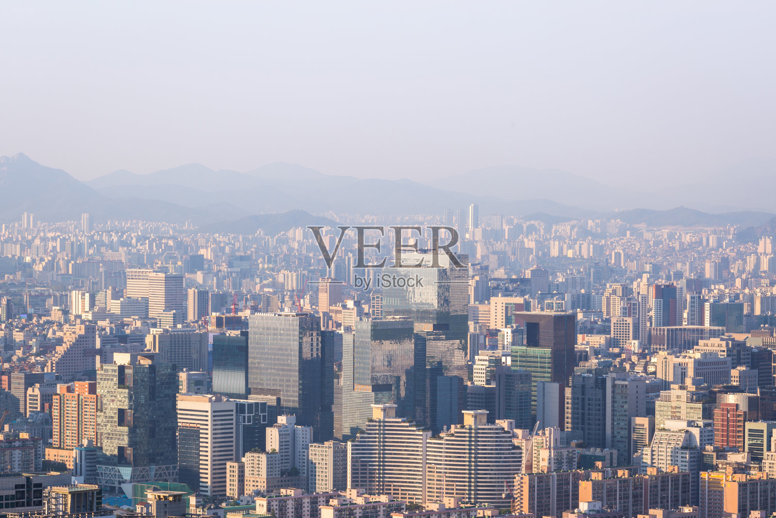 下午，以雾和北韩山为背景的首尔市和江南区的摩天大楼。照片摄影图片