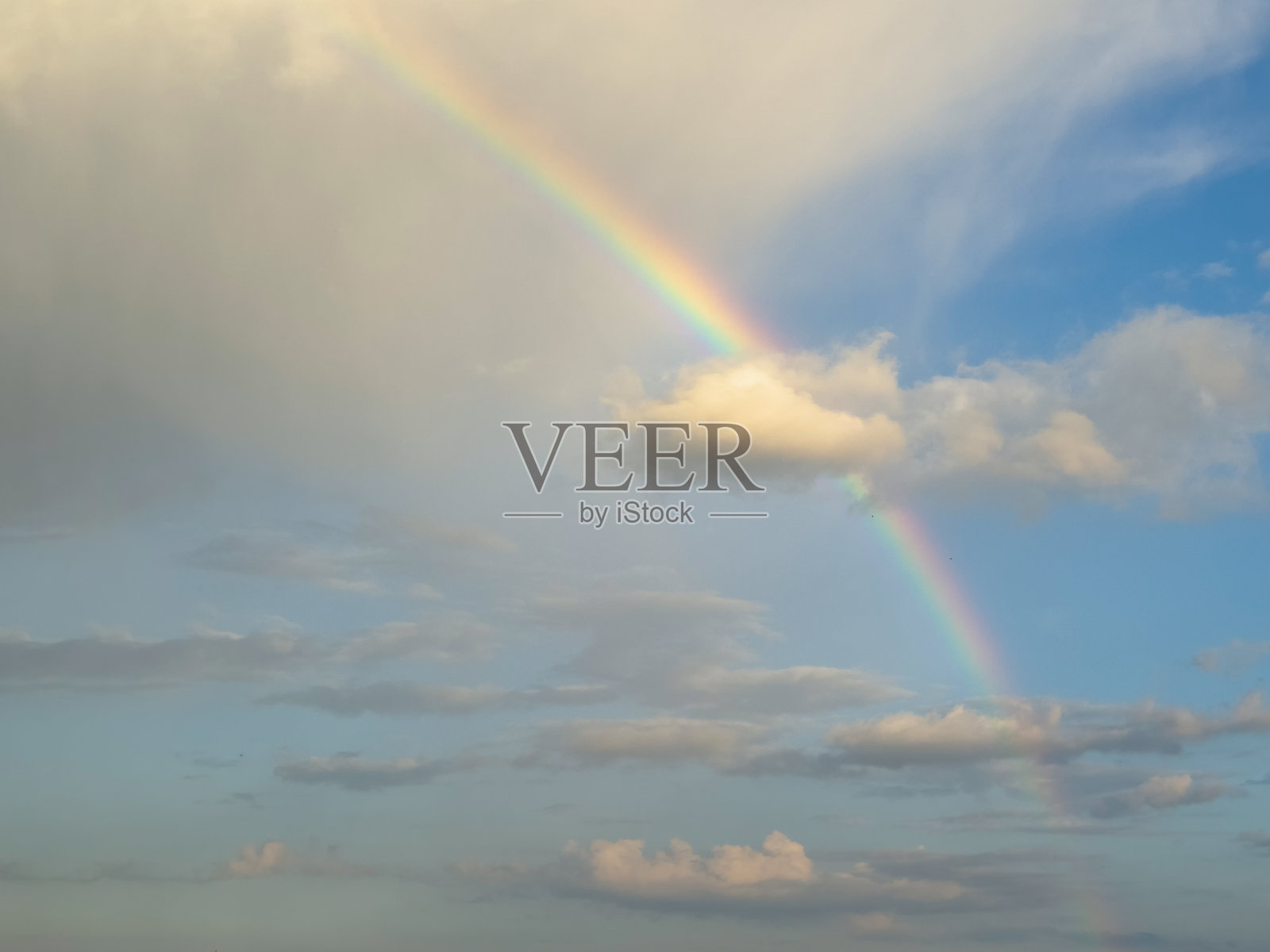 美丽的彩虹在云层之上的天空。照片摄影图片