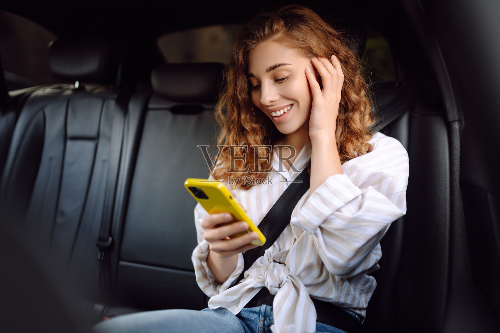 系安全带的女士在车内打电话。照片摄影图片