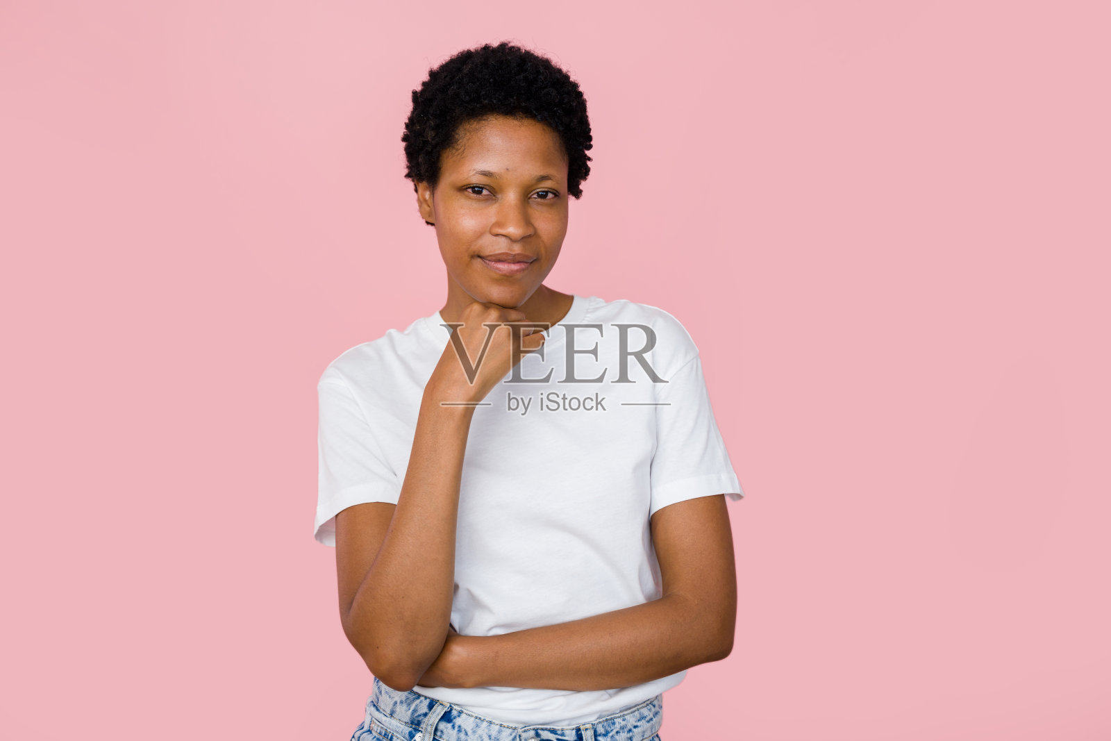 年轻的黑人女性在粉红色的背景上把手放在下巴上摆姿势照片摄影图片