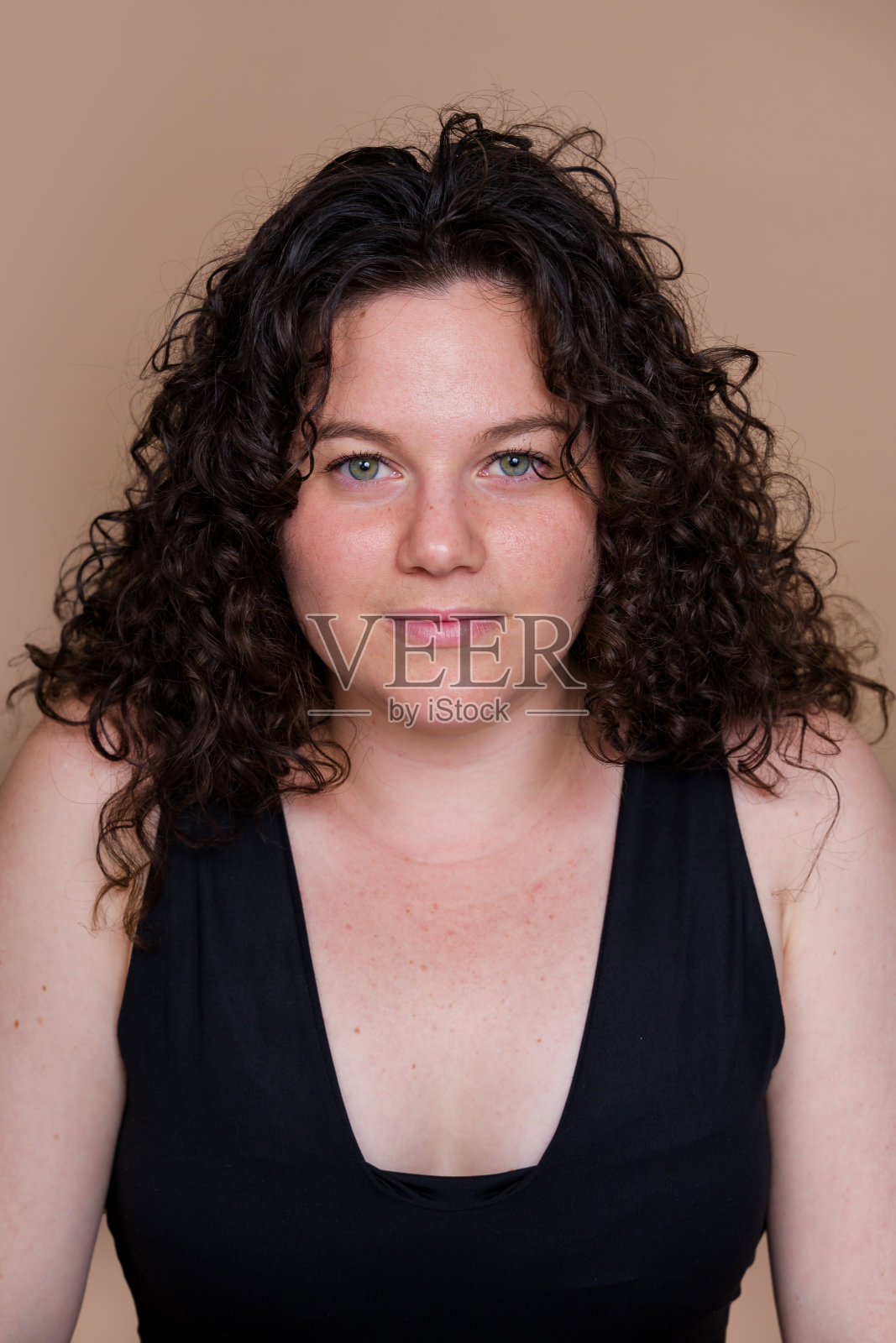 在米色背景上摆姿势的女人表情严肃照片摄影图片