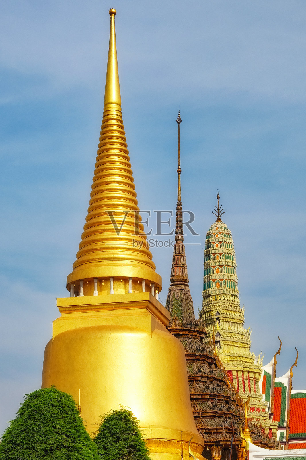 泰国一座有金色尖塔的寺庙。这座寺庙有一个巨大的金色尖塔。天空是蓝色的，寺庙沐浴在阳光下。照片摄影图片