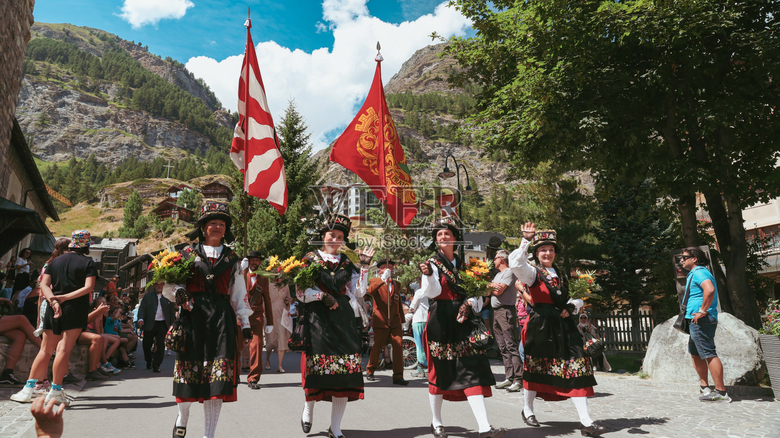 采尔马特五彩缤纷的民间节日游行，身着传统服装，挂着充满活力的横幅照片摄影图片