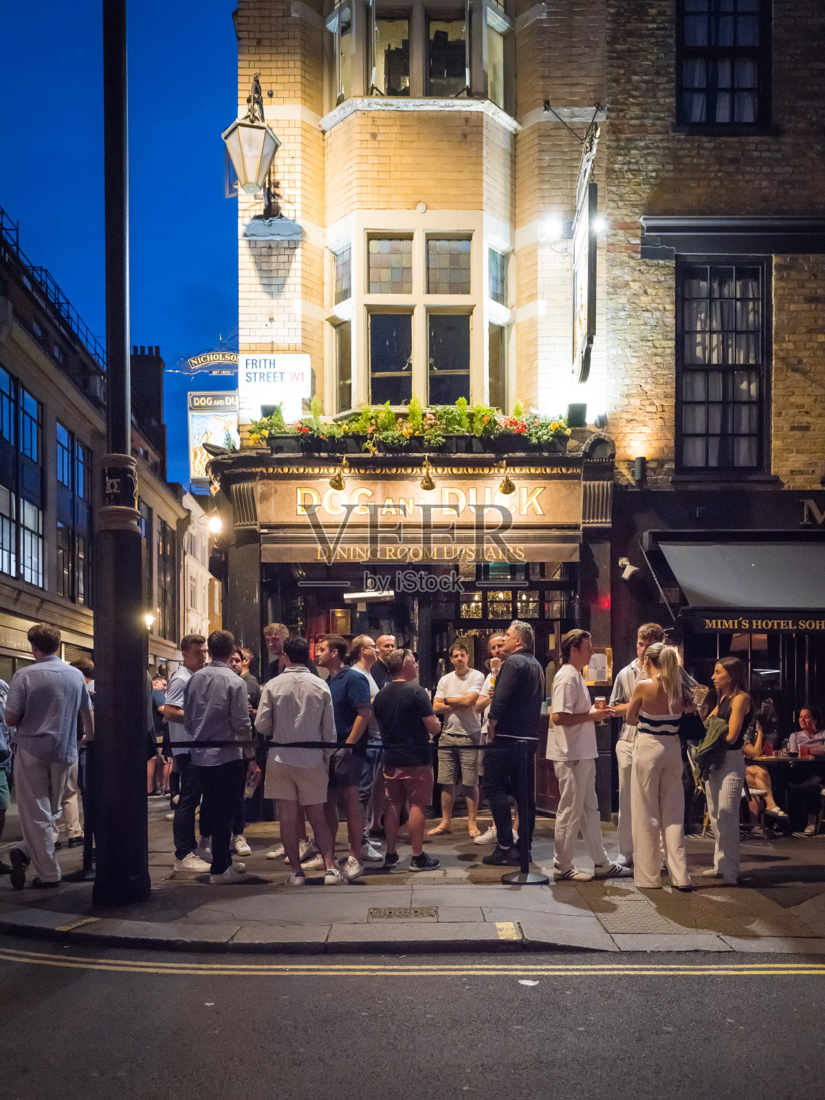 伦敦苏荷区的夜晚，在繁忙的传统酒吧外，成群的饮酒者照片摄影图片