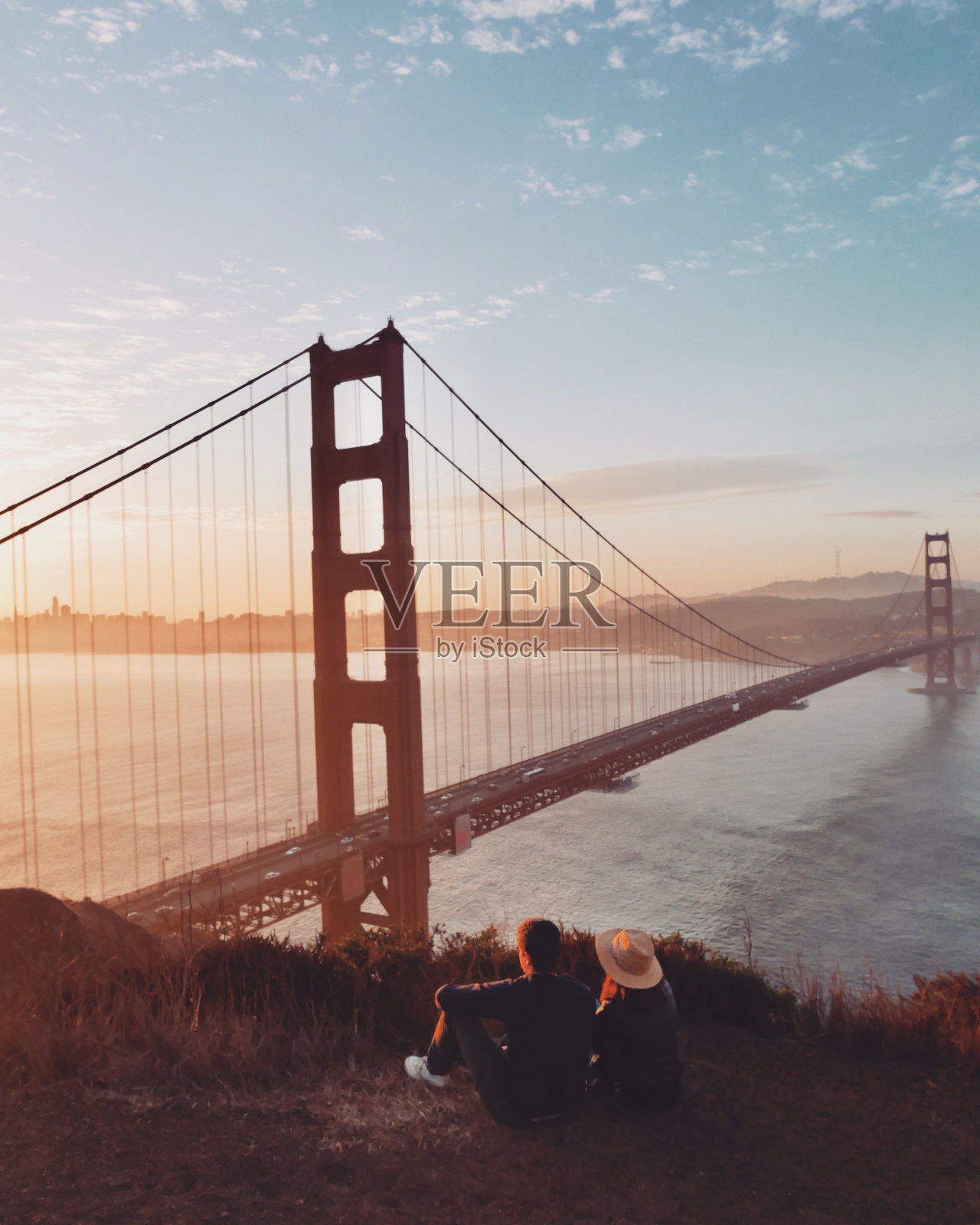 一对夫妇背对天空坐在桥上的后视图照片摄影图片