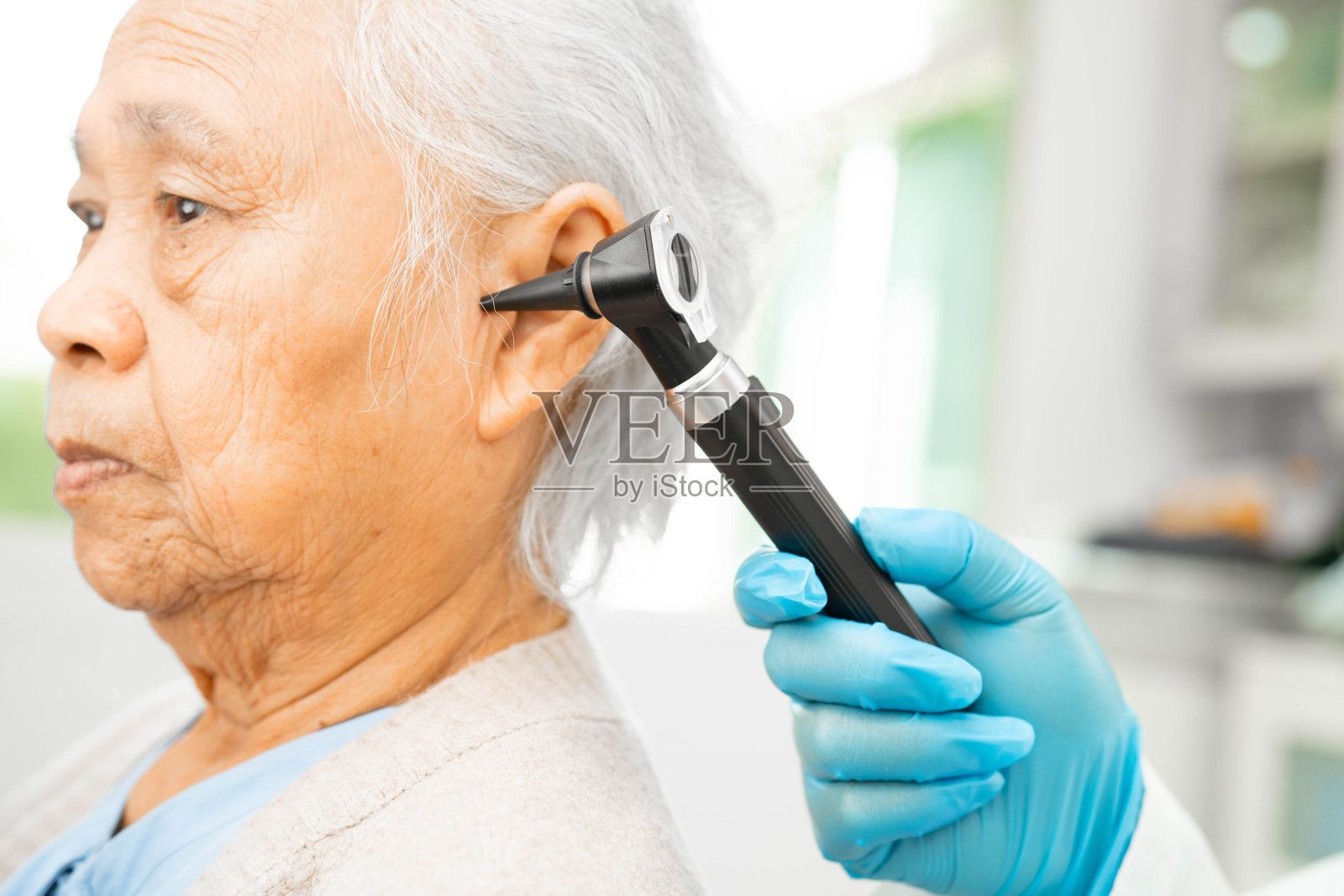 听力学家使用耳镜检查老年妇女患者的耳朵，治疗听力损失问题。照片摄影图片