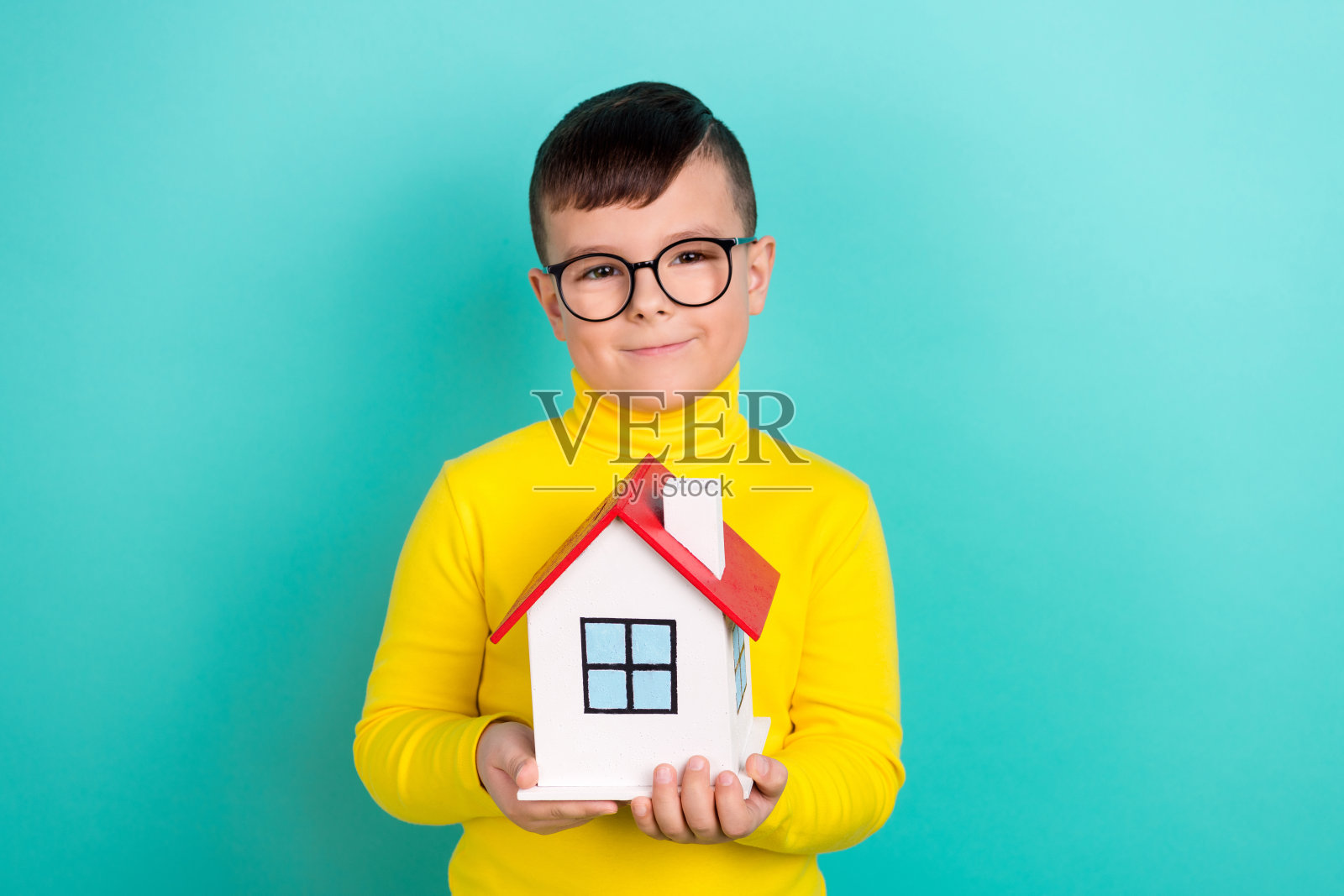 可爱的男孩抱着房子的照片家庭收养贷款提供概念孤立的青色背景照片摄影图片
