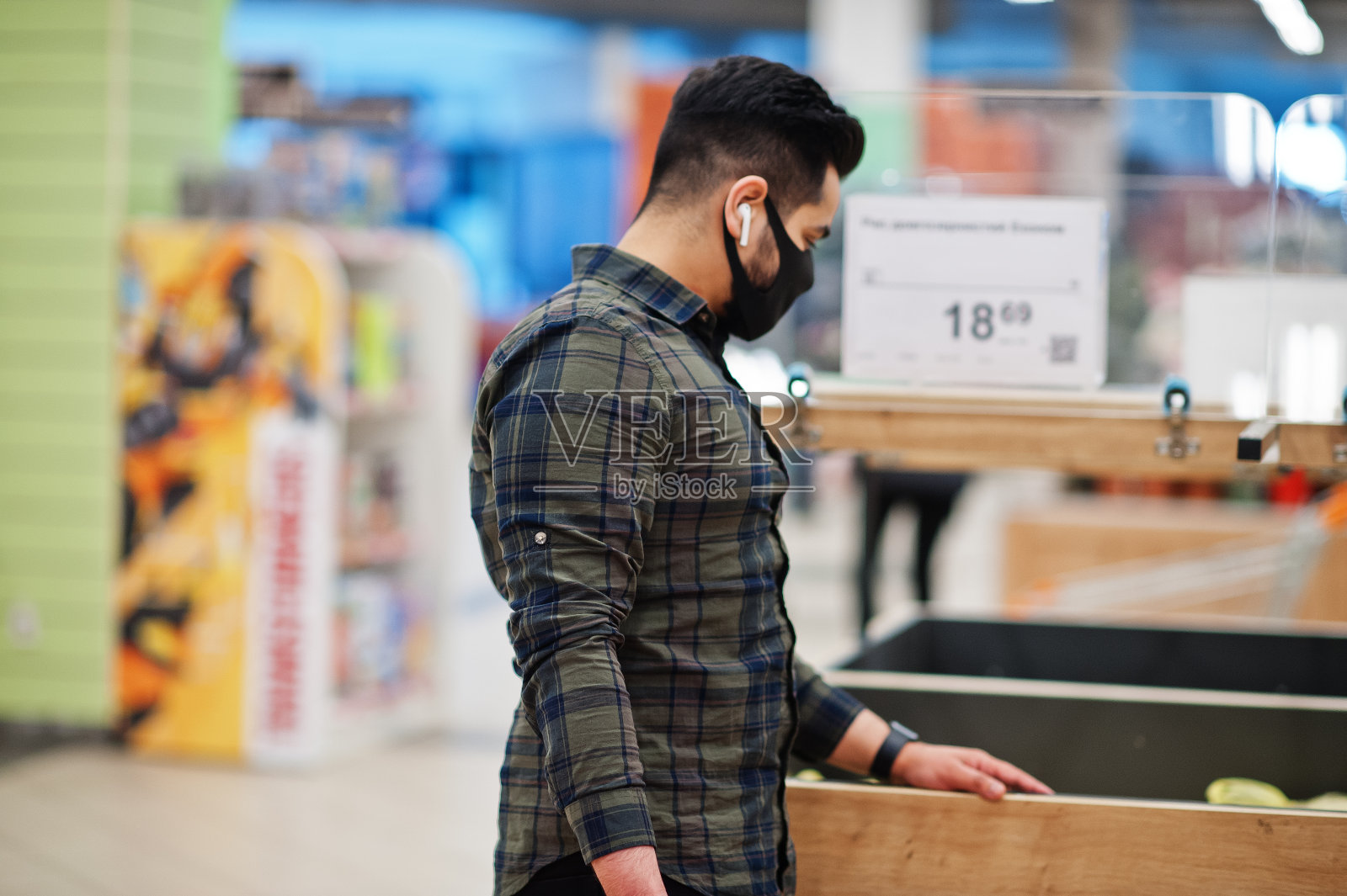 亚洲男子在流感大流行期间在超市内戴防护口罩购物。照片摄影图片