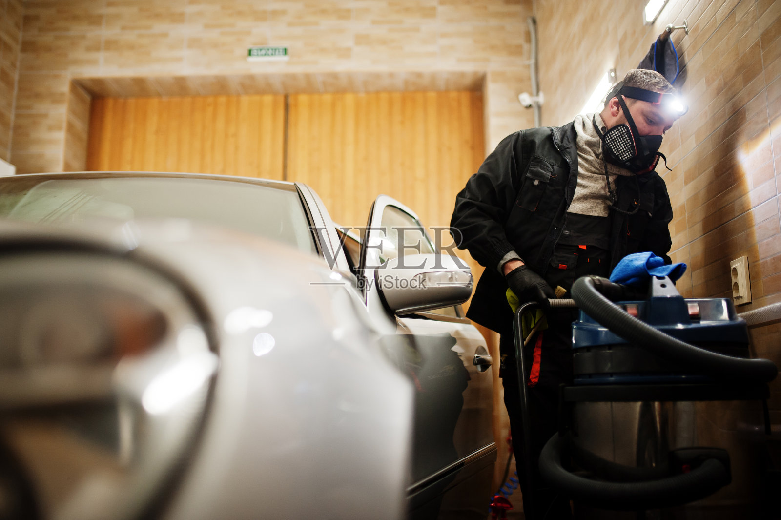 穿制服带防毒面具的人，洗车中心工人，用热蒸汽清洗机清洗车内。汽车细节概念。照片摄影图片