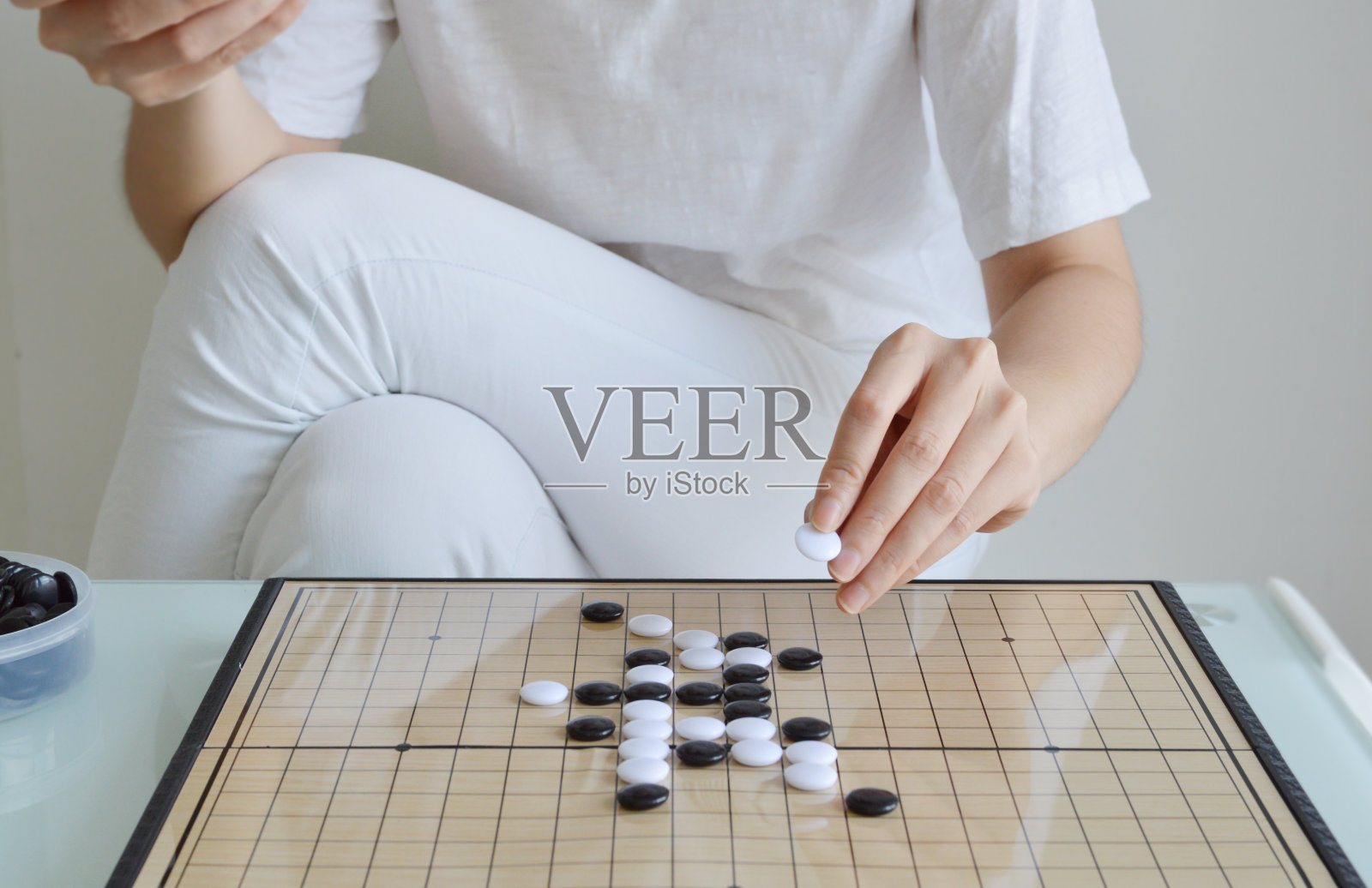 直观围棋棋盘游戏桌与女子手握石头照片摄影图片