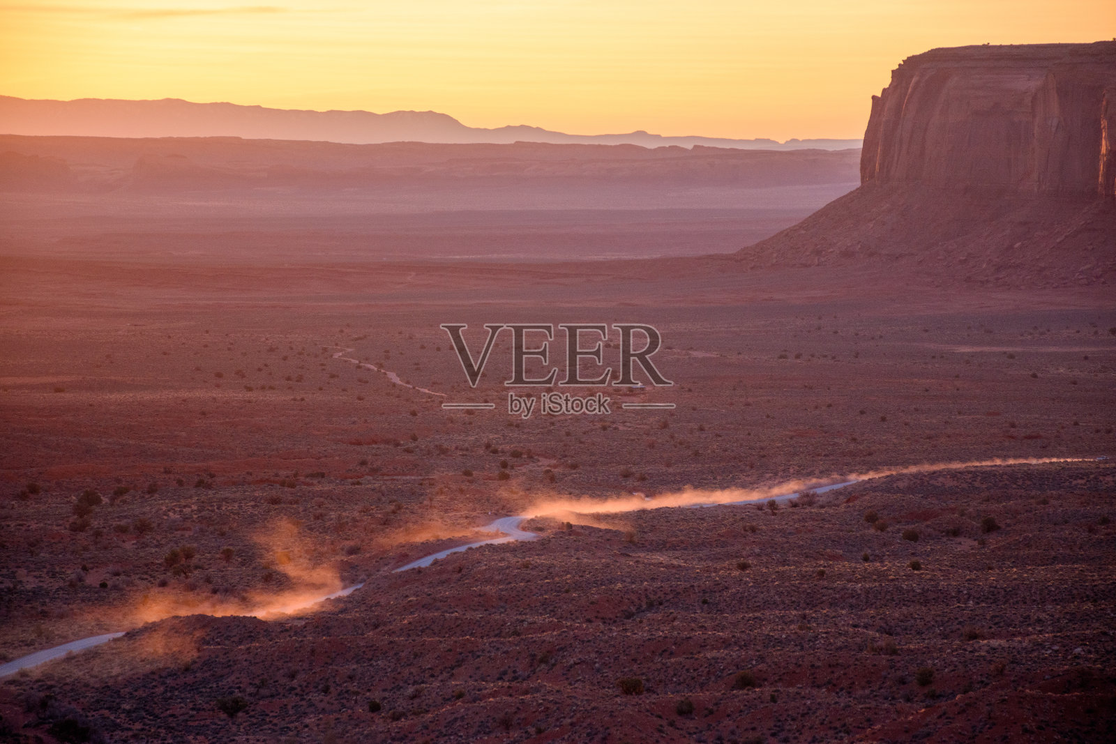 黎明时分驱车穿过纪念碑谷，沿途尘土飞扬照片摄影图片