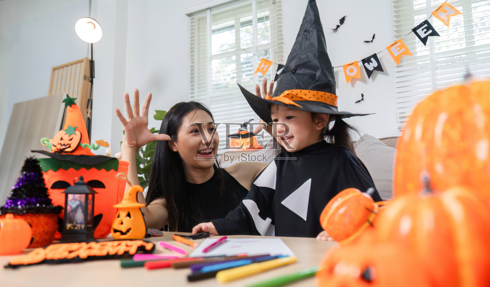 妈妈和女儿用南瓜、服装和节日装饰品装饰客厅照片摄影图片