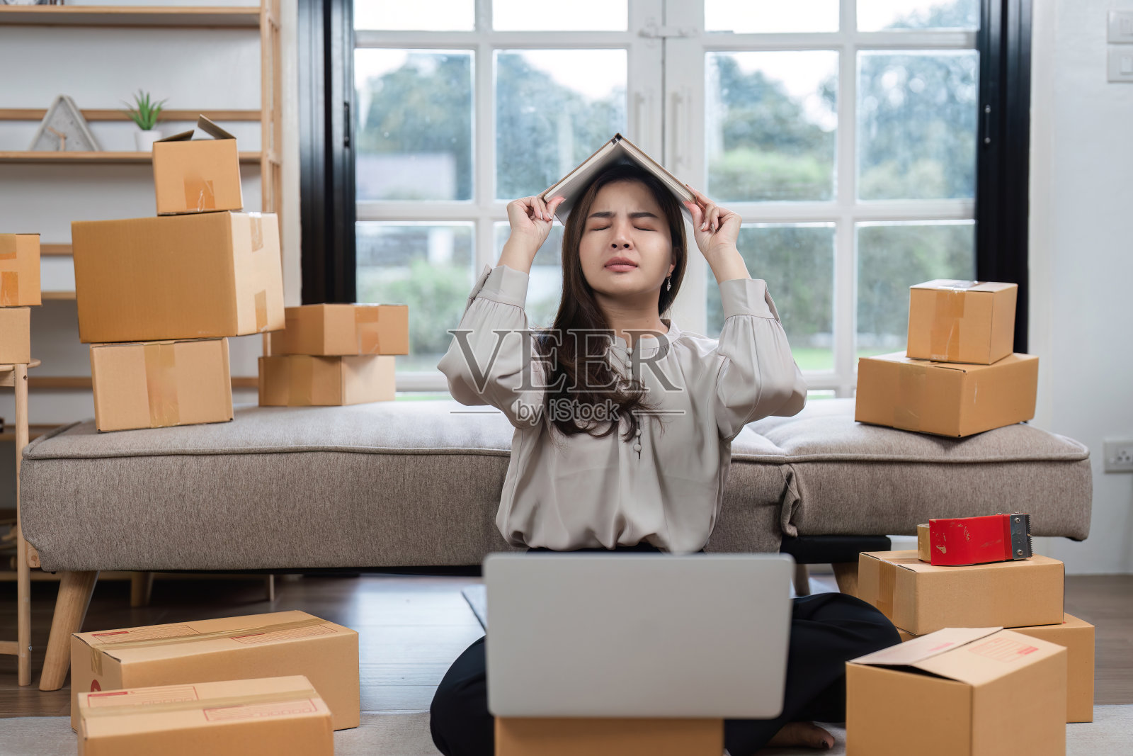 在现代家庭办公环境中，被盒子包围的年轻女子在网上订购时感到疲倦照片摄影图片