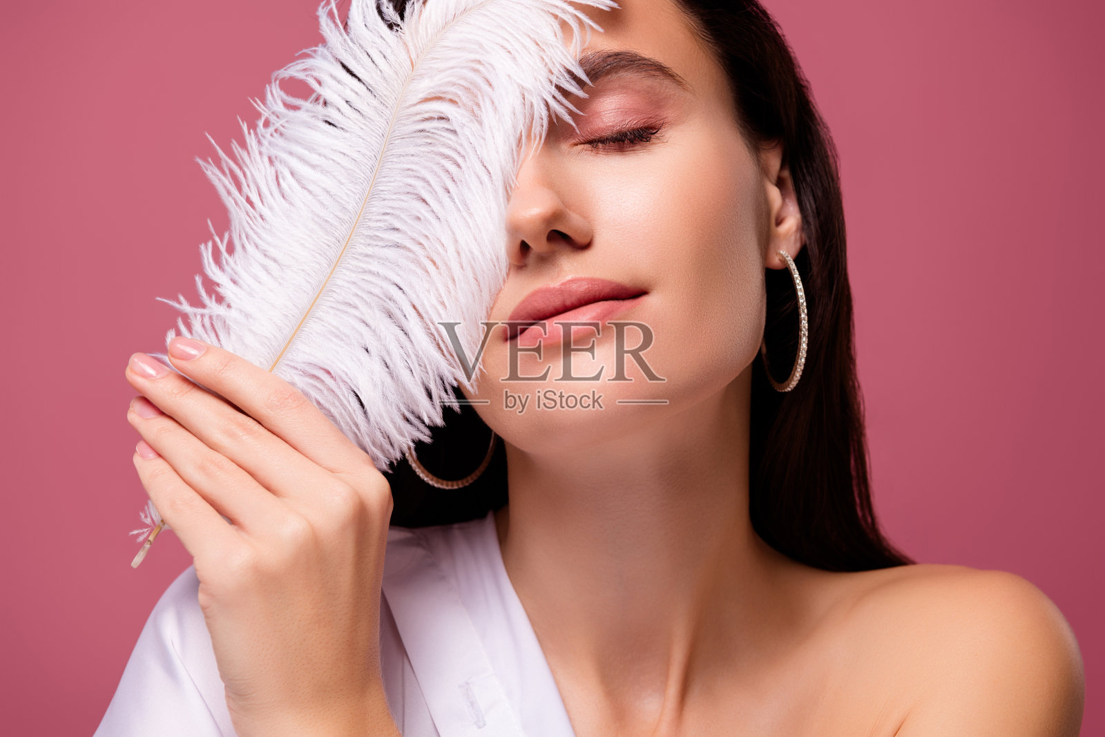 女孩的肖像触摸覆盖脸白色羽毛感觉皮肤温柔孤立粉红色的背景照片摄影图片