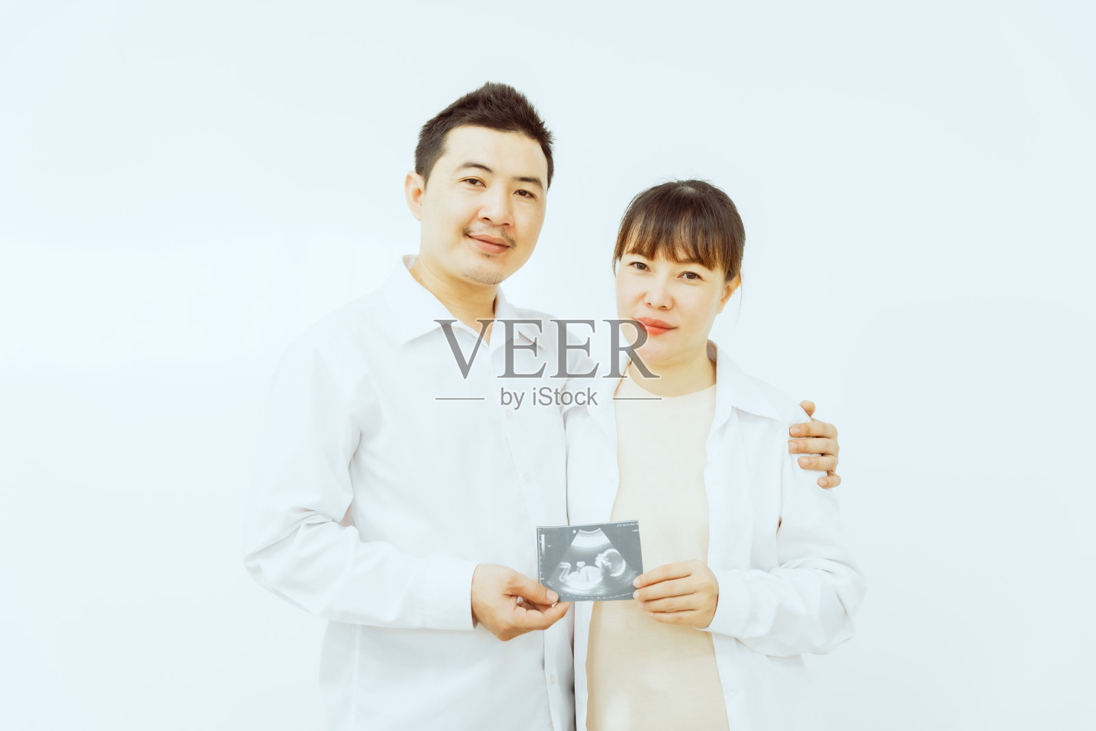 一对亚洲中年夫妇和怀孕的妻子深情地拥抱在一起，脸上洋溢着对即将到来的孩子的幸福和期待，象征着家庭的团聚和喜悦。照片摄影图片