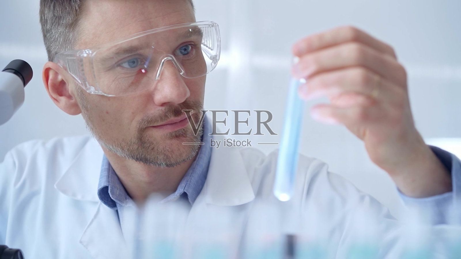 戴着防护眼镜检查试管的科学家研究员照片摄影图片