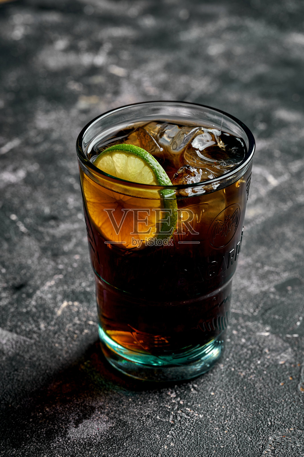 一杯朗姆酒和可乐，放在木桌上，还有冰块和青柠角。照片摄影图片