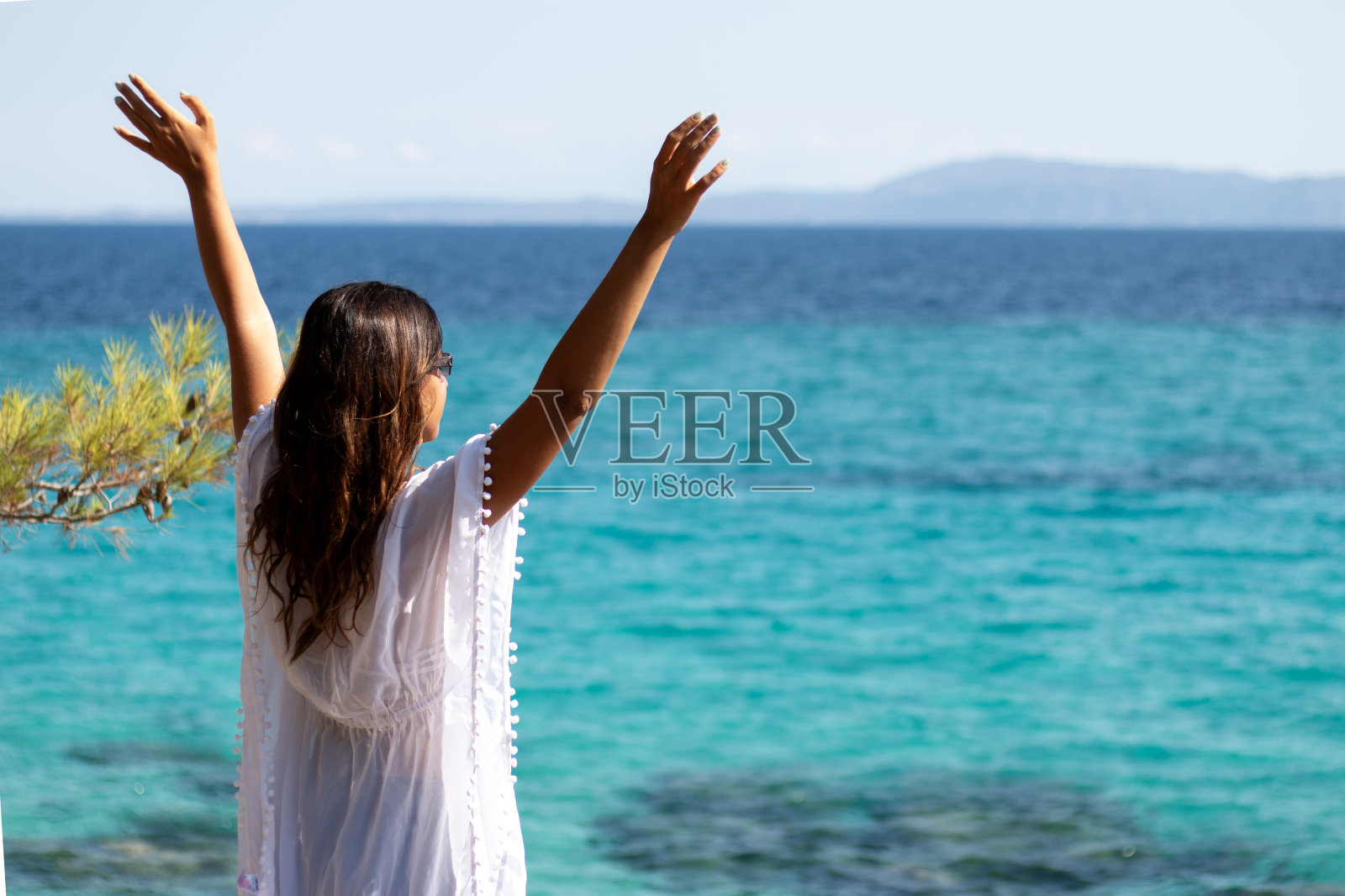 快乐的年轻女子举起双手，享受着夏日的美景。照片摄影图片