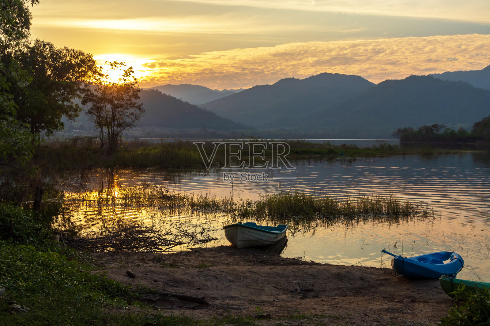 日落时分，泰国Ratchaburi的Tha Khoei水库的美丽风景与山脉在水面上的反射。照片摄影图片