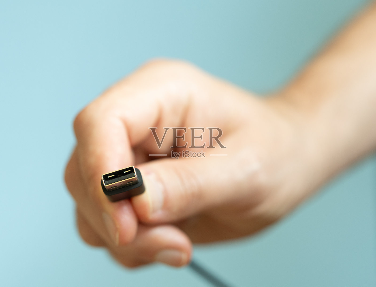 男子手持USB线，蓝色背景，科技理念照片摄影图片