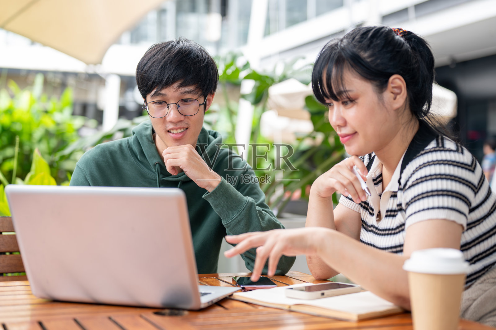 两个年轻的亚洲大学生正在一起讨论工作和做一个合作项目。照片摄影图片