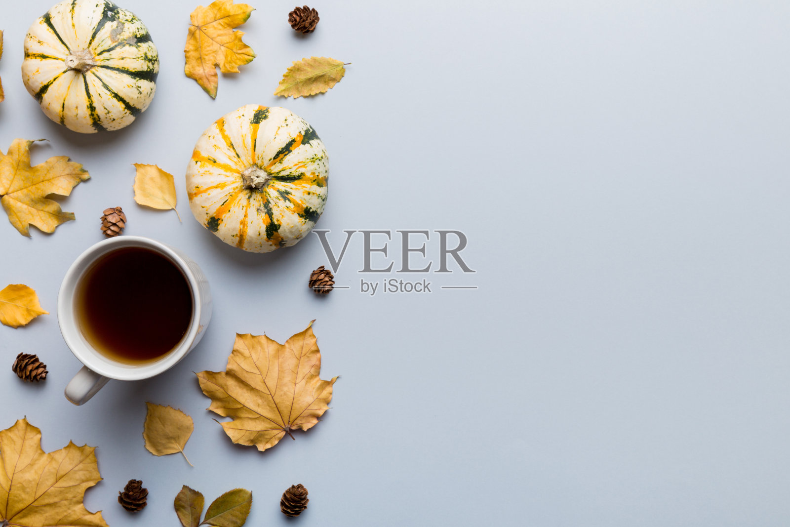 在彩色背景上，用五彩缤纷的秋杯咖啡和树叶平铺构图。俯视图照片摄影图片