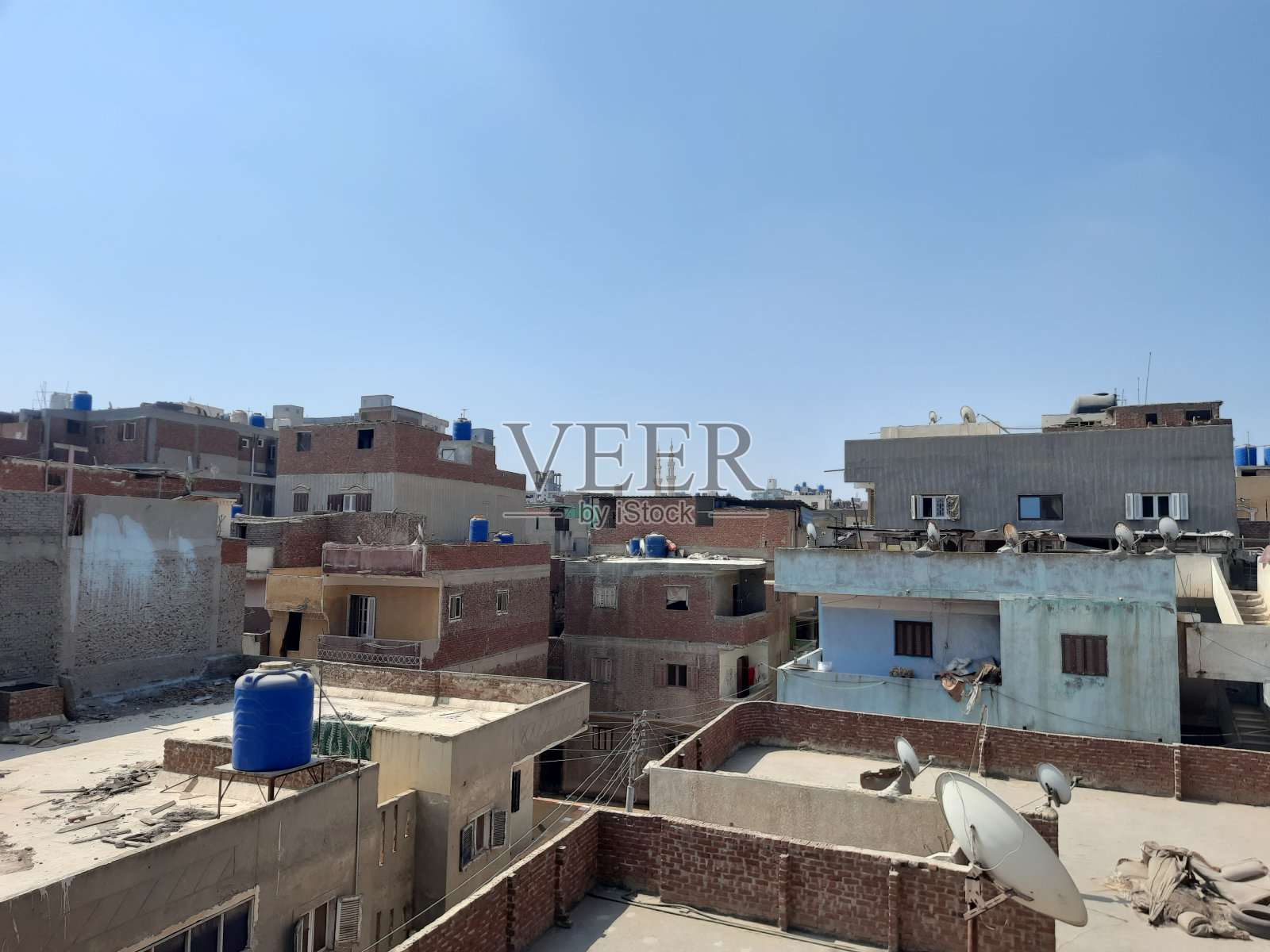 埃及小城市白天的建筑屋顶、卫星天线和水箱，晴朗的蓝天，埃及城市建筑照片摄影图片