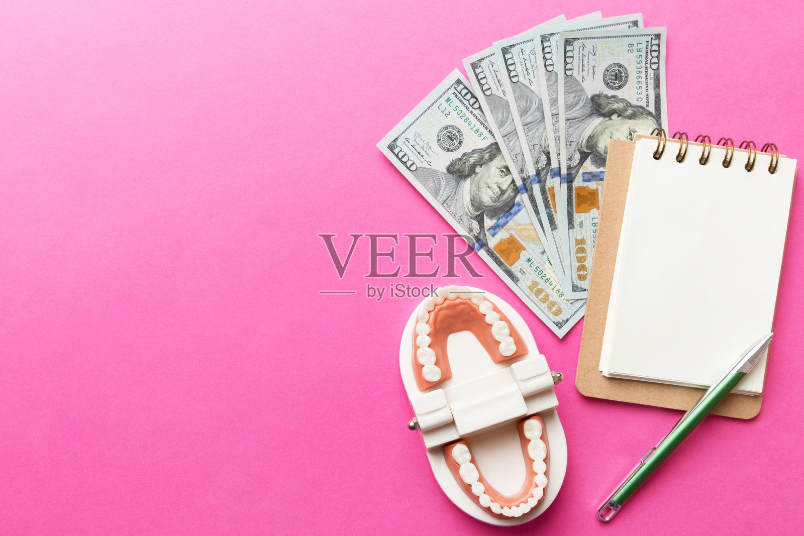 在彩色的桌子上，俯视图上平铺着教育牙科印刷模型和钱与笔记本。昂贵的治疗照片摄影图片