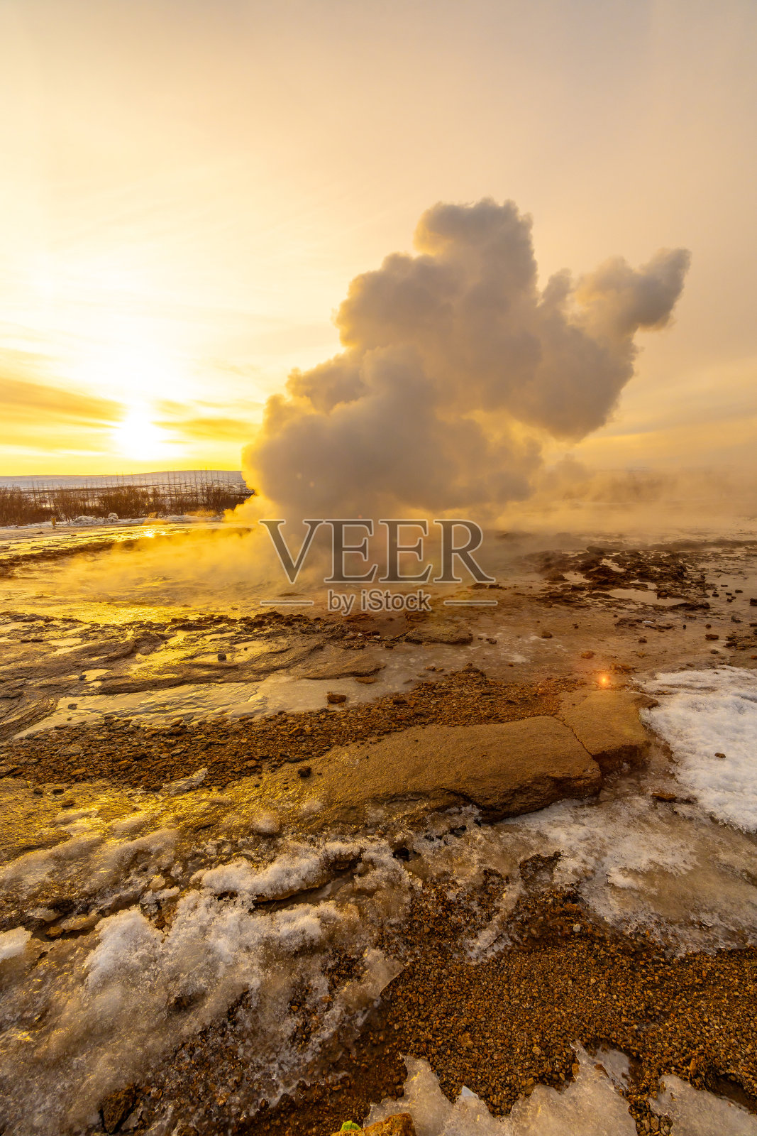 日出时斯特鲁克间歇泉喷发。冰岛的冬天非常寒冷照片摄影图片