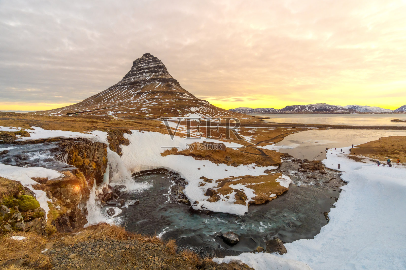 冬天，冰岛著名的Kirkjufell山上的日出，旁边是瀑布照片摄影图片