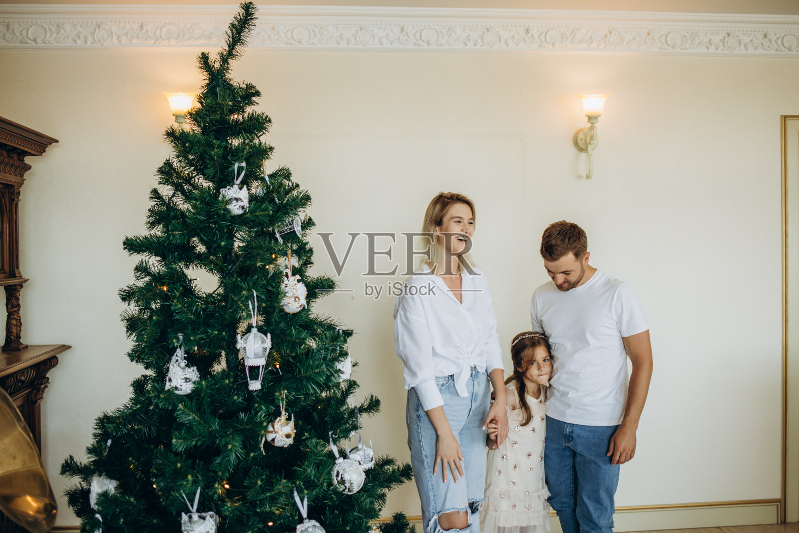 幸福的一家人在家里圣诞树旁戴着圣诞老人的帽子照片摄影图片