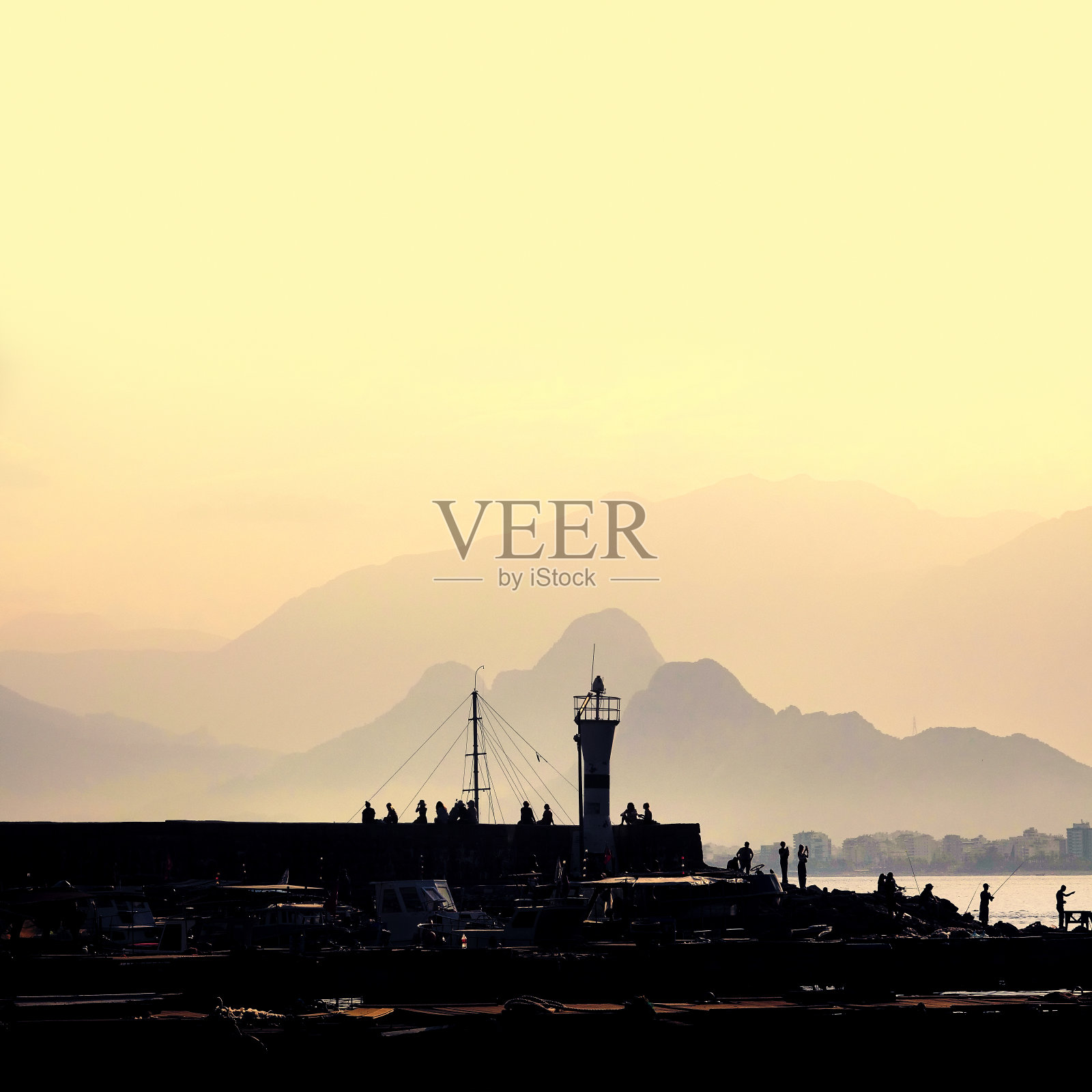 人们在日落时分走在码头上照片摄影图片