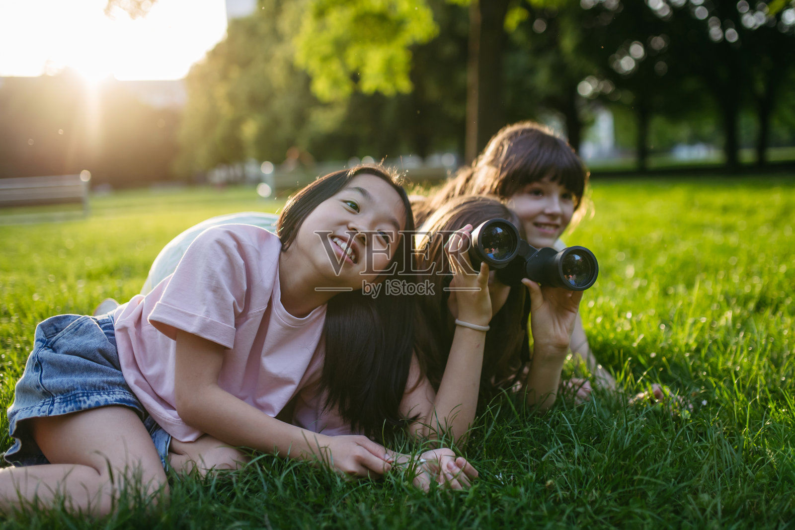 年轻的女学生在城市环境中学习自然和野生动物，使用双筒望远镜和在公园观察动物。照片摄影图片