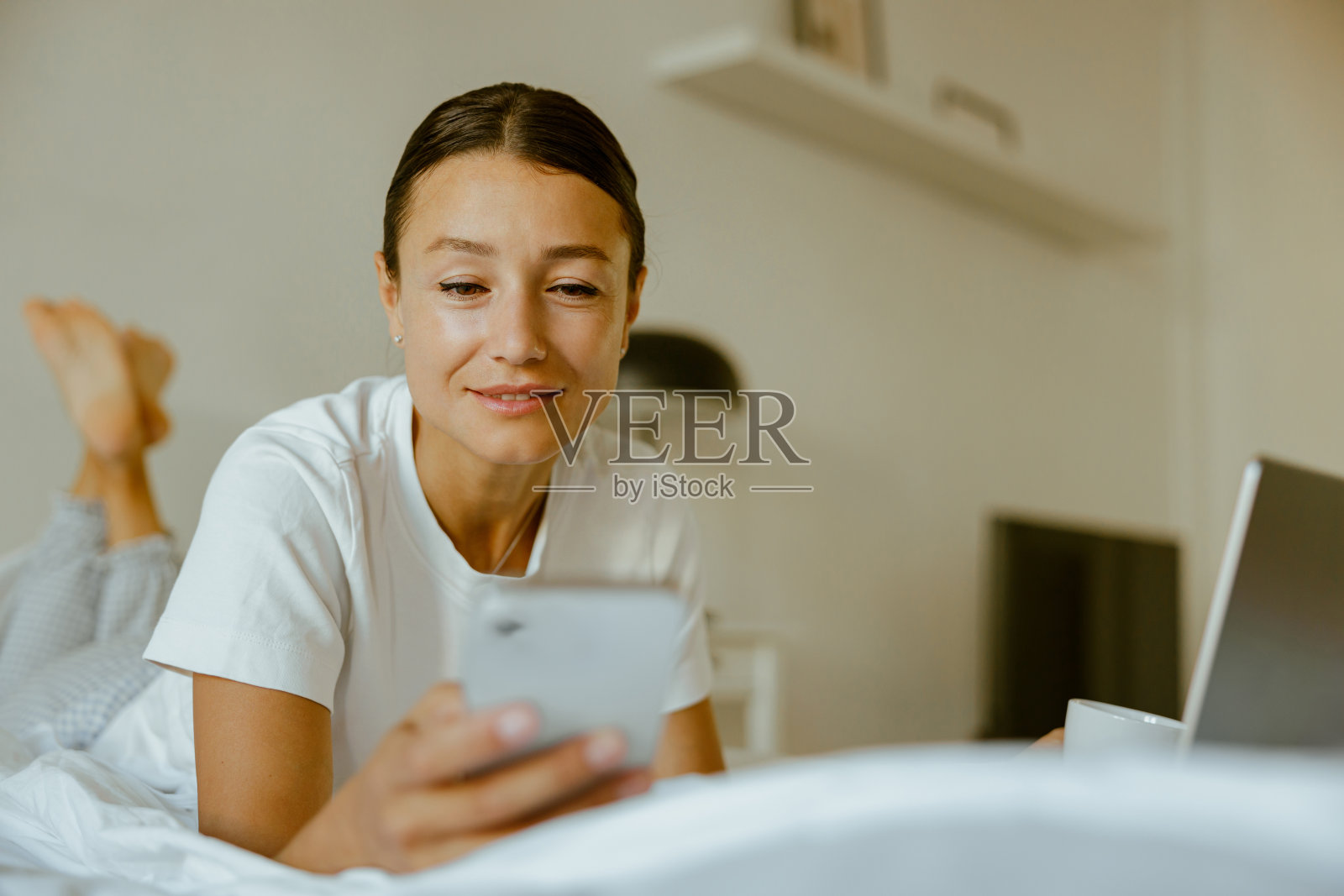 一个女人在家里舒适地放松，同时使用她的手机和笔记本电脑照片摄影图片