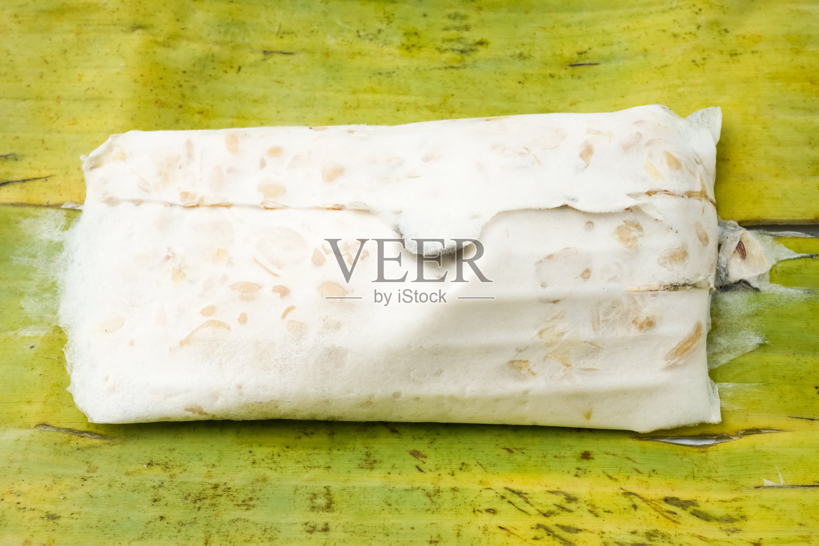 传统的豆豉包在香蕉叶里。天贝是一种传统的印尼食品，由发酵的大豆和特殊的酵母霉菌制成。植物蛋白和植物性食物的概念。照片摄影图片
