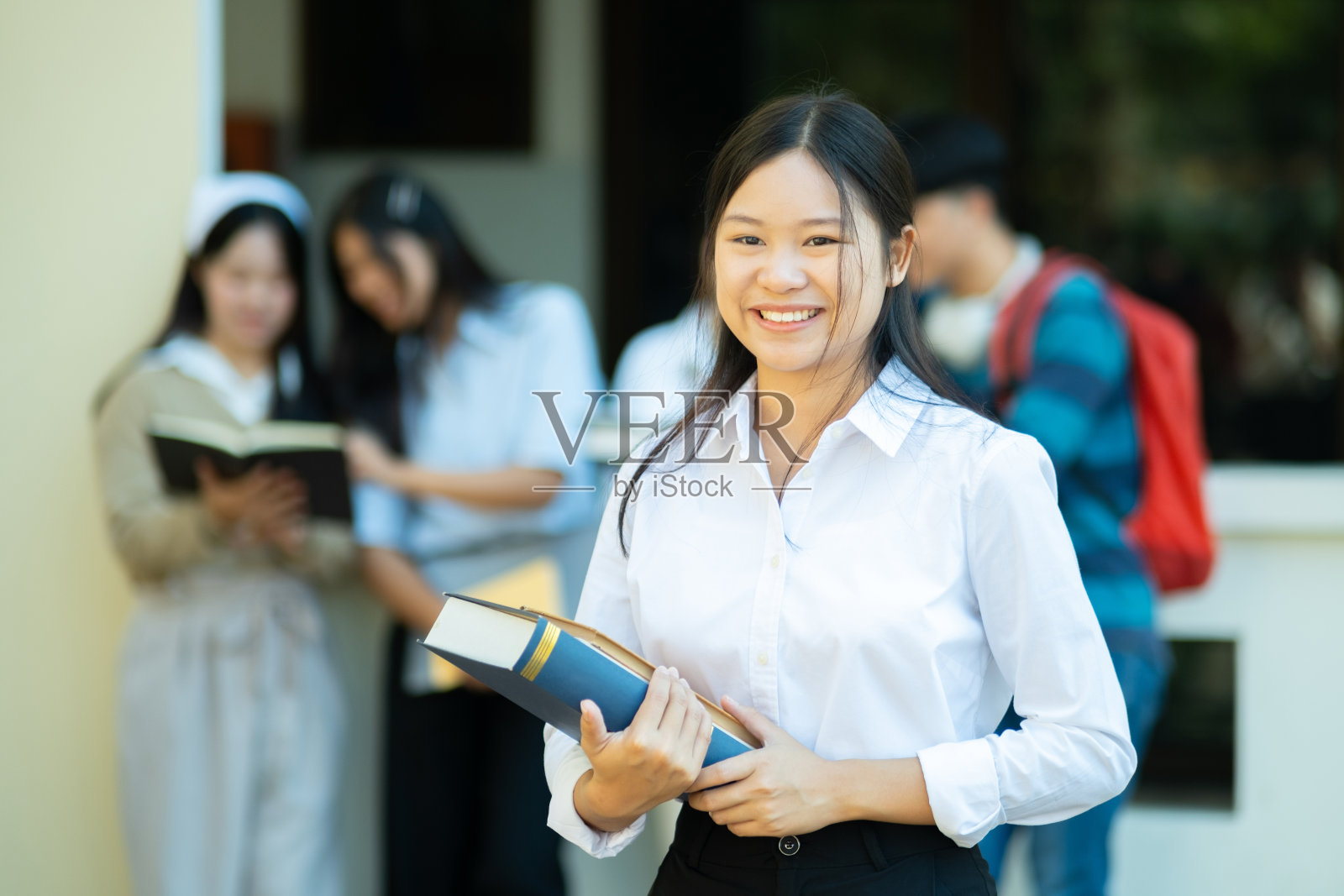 微笑的学生在校园里拿着书照片摄影图片