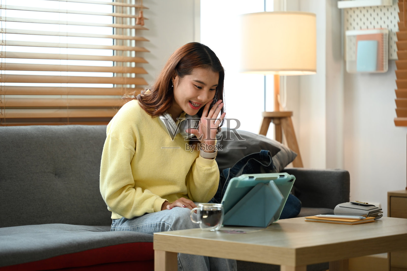 快乐的亚洲女人在家里用平板电脑和朋友视频通话照片摄影图片