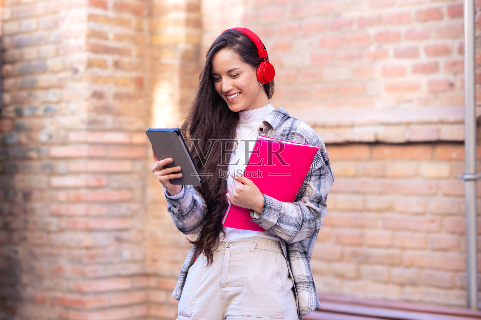 快乐的年轻拉丁妇女在户外使用数字平板电脑浏览互联网。照片摄影图片