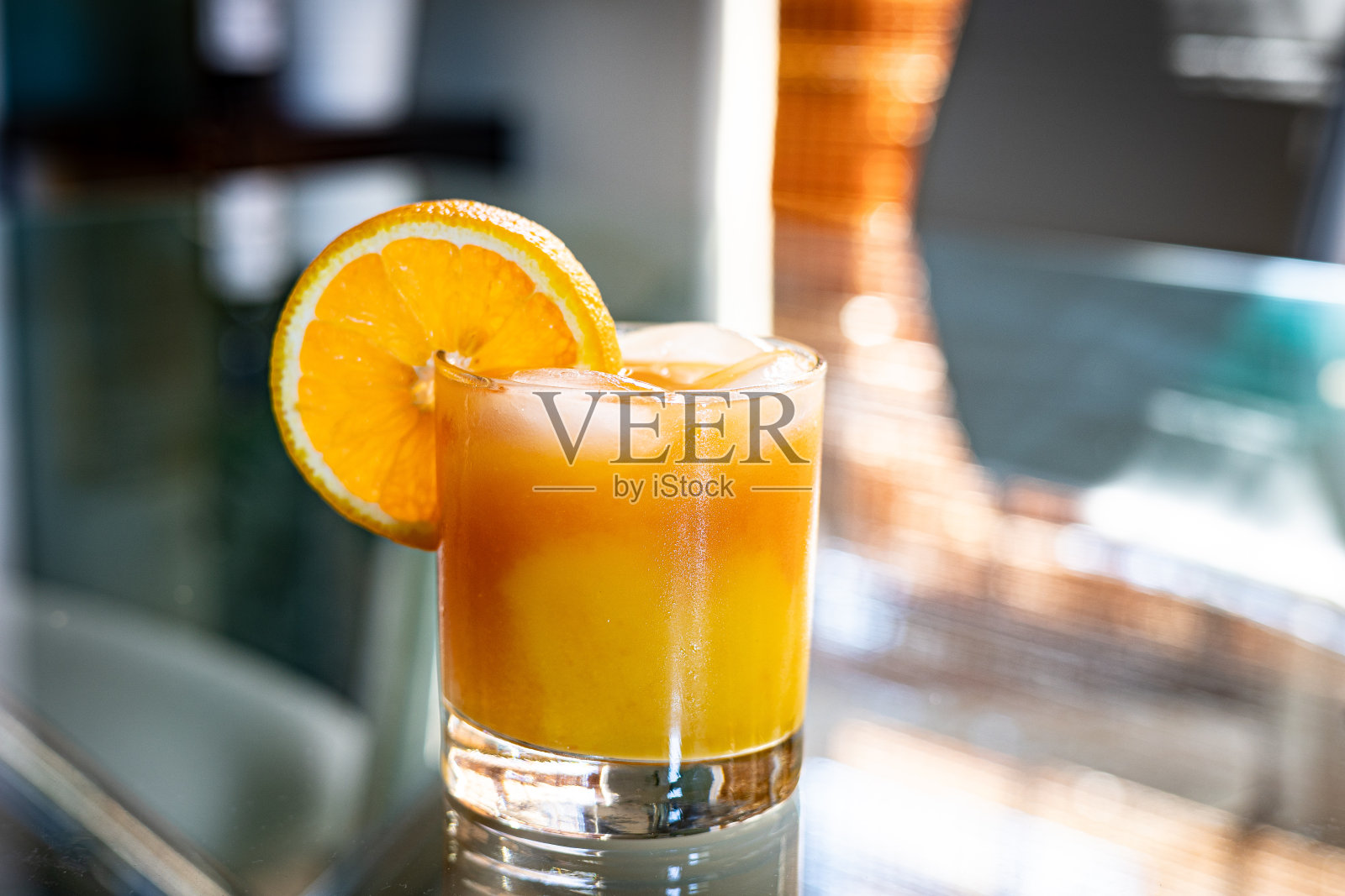 一杯橙西柚汁无酒精鸡尾酒，配上一片柑橘片，放在玻璃桌上。照片摄影图片