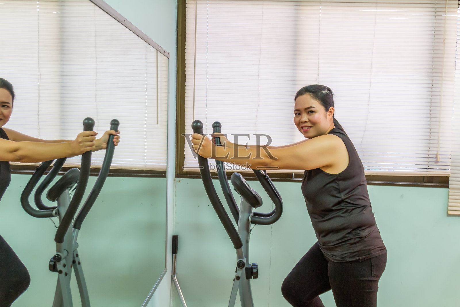 微笑的女人在健身房用镜子锻炼照片摄影图片