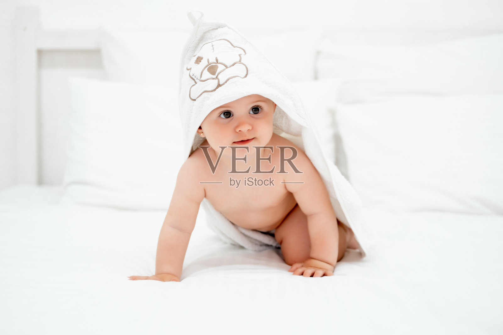 家里白色的床上裹着毛巾的婴儿，明亮的卧室里沐浴后微笑的孩子，文字的空间照片摄影图片